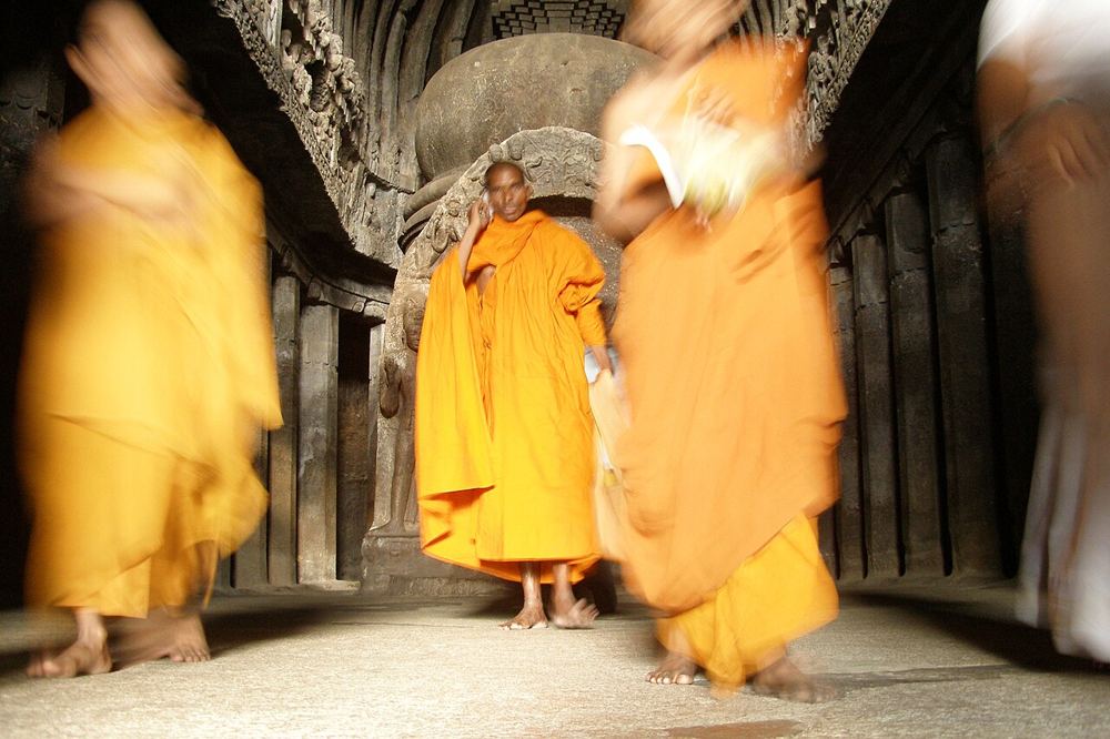 Monks walking through a rock-cut hall at Ellora
