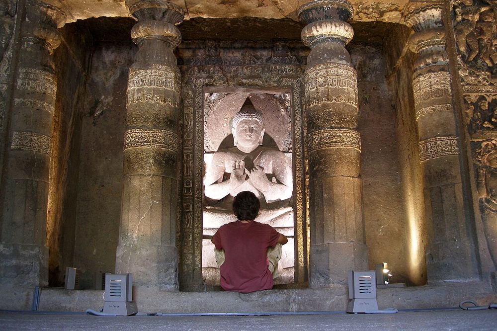 A visitor before a carved Buddha at Ajanta